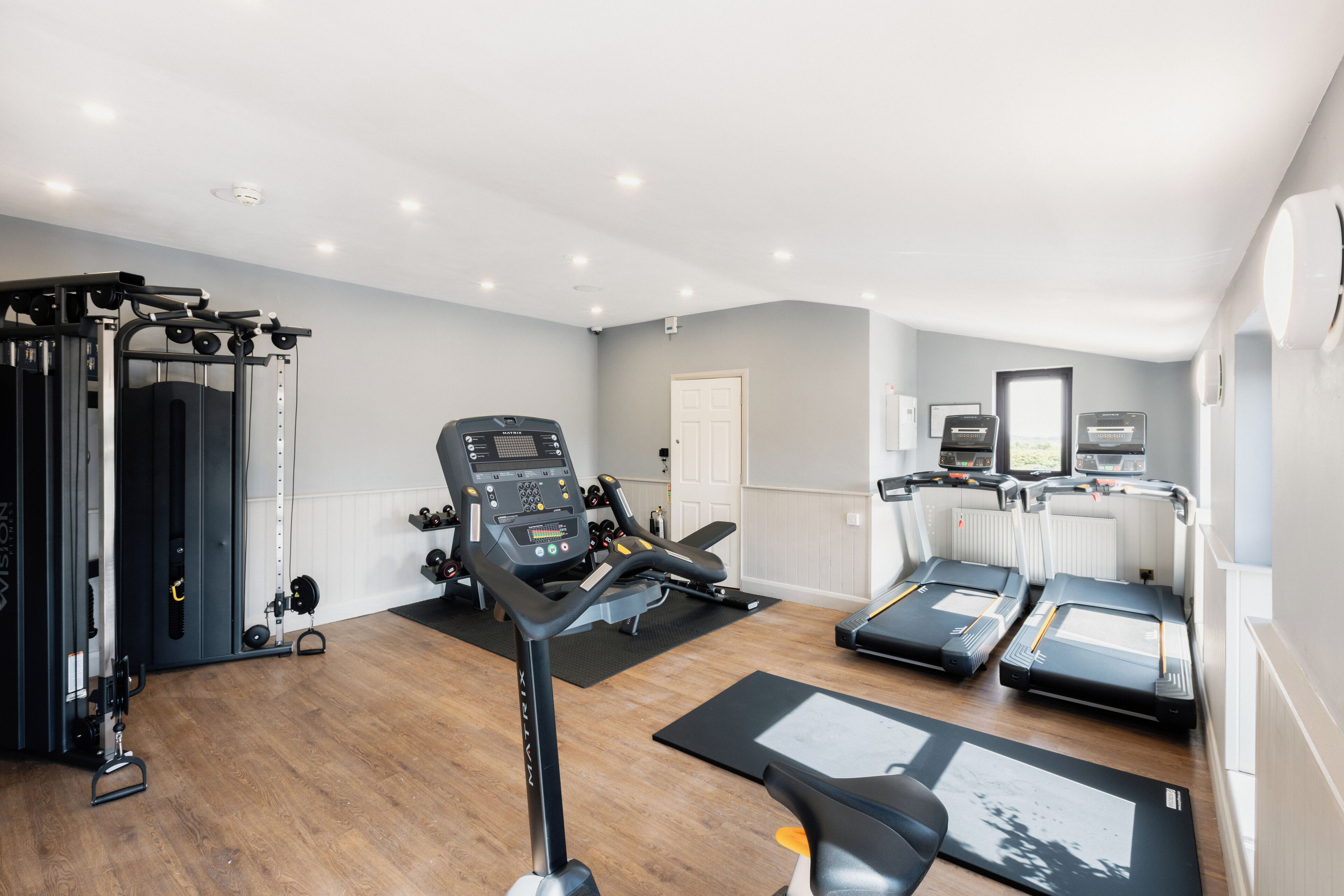 Uma academia em casa com esteira, banco de musculação e diversos equipamentos de exercício.