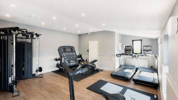 Uma academia em casa com esteira, banco de musculação e diversos equipamentos de exercício.