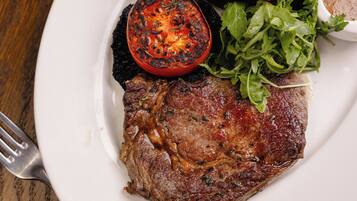 A plate with a steak, fries, and a grilled tomato.