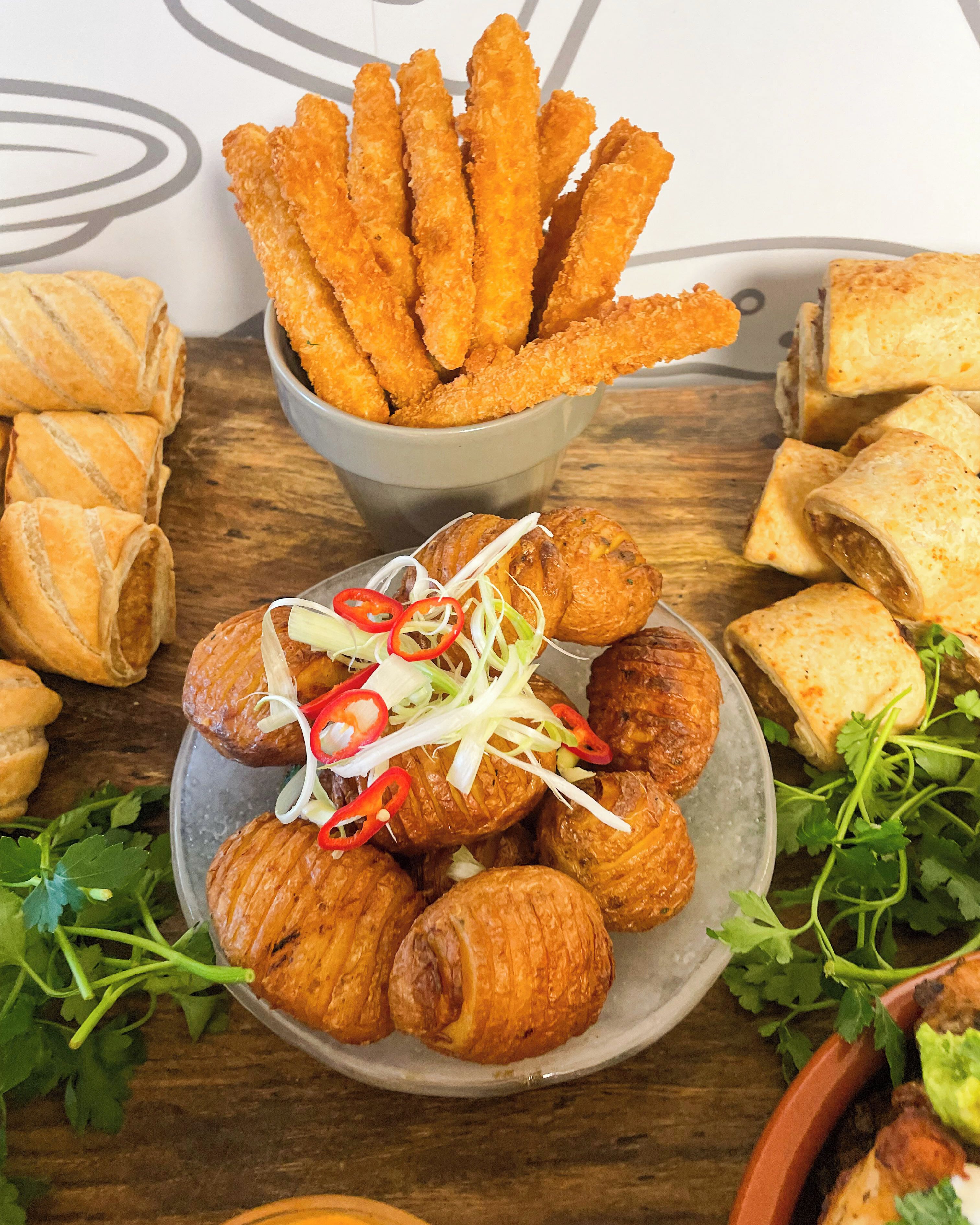 Diverse gebakken snacks en patisserie op een houten tafel.