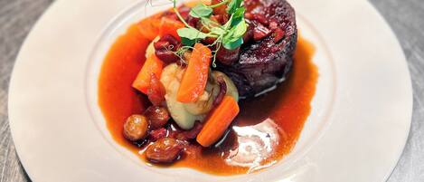 A plate of food with a piece of meat, vegetables, and a sauce.