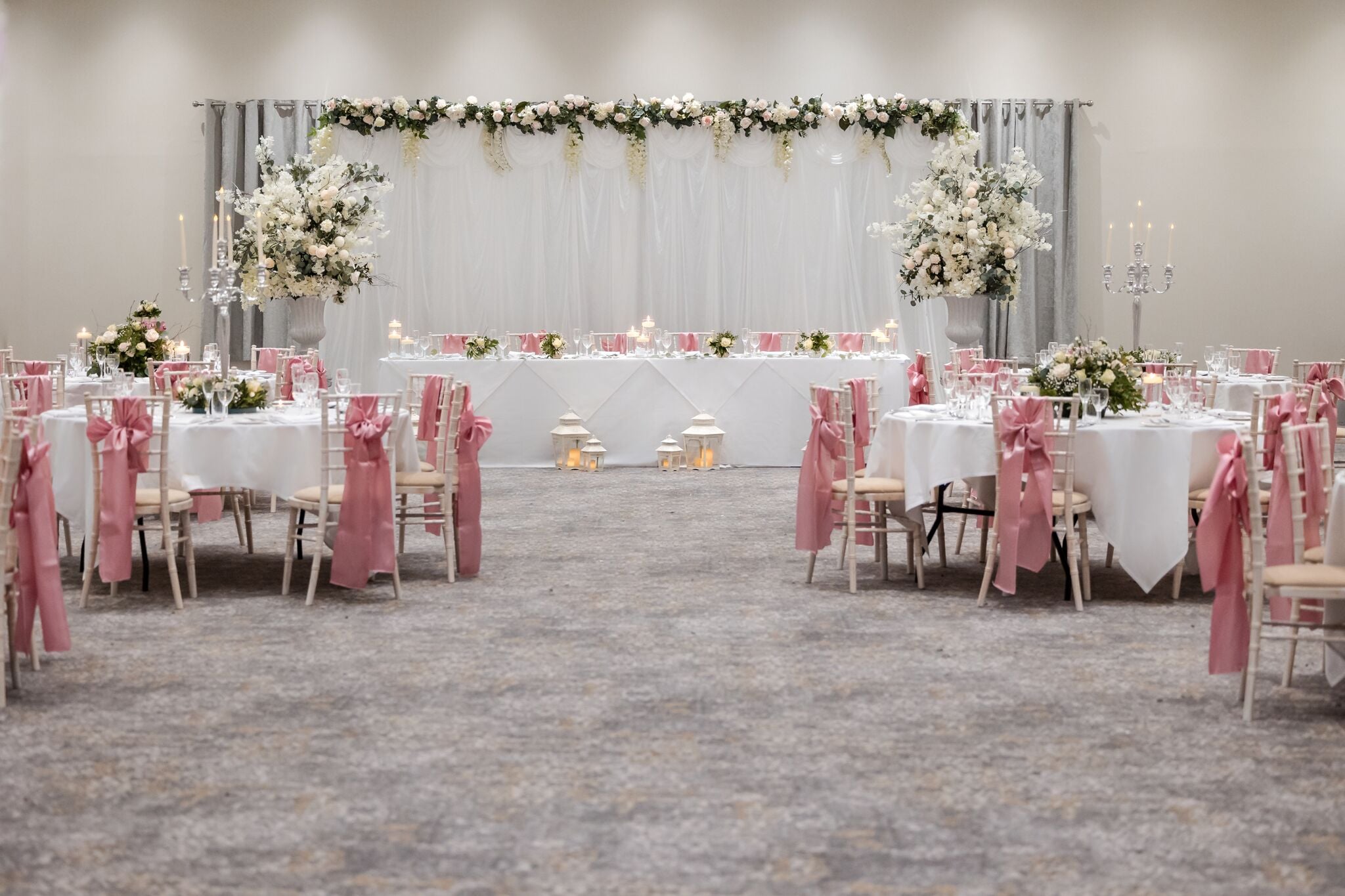 A formal event space with round tables, chairs, and floral centerpieces.