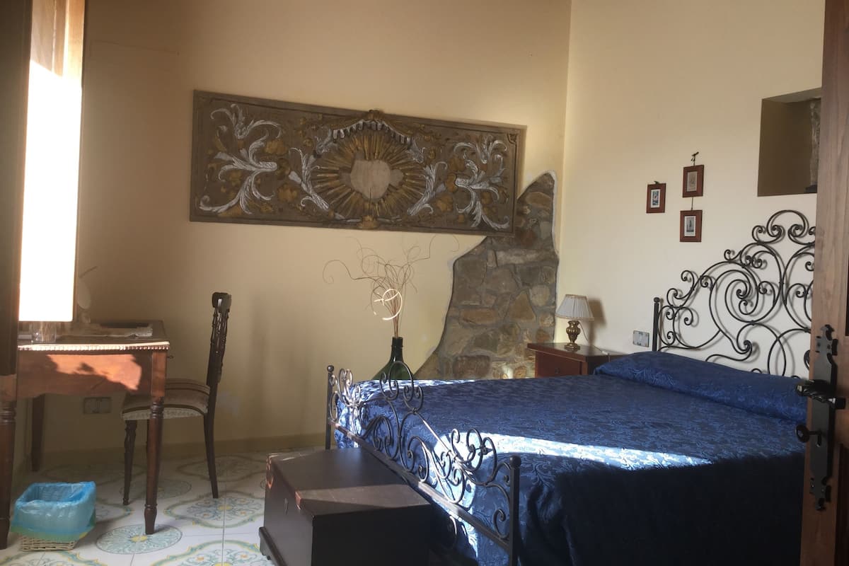 Une chambre à coucher comprenant un lit, un bureau, une chaise, une lampe et un élément décoratif mural.