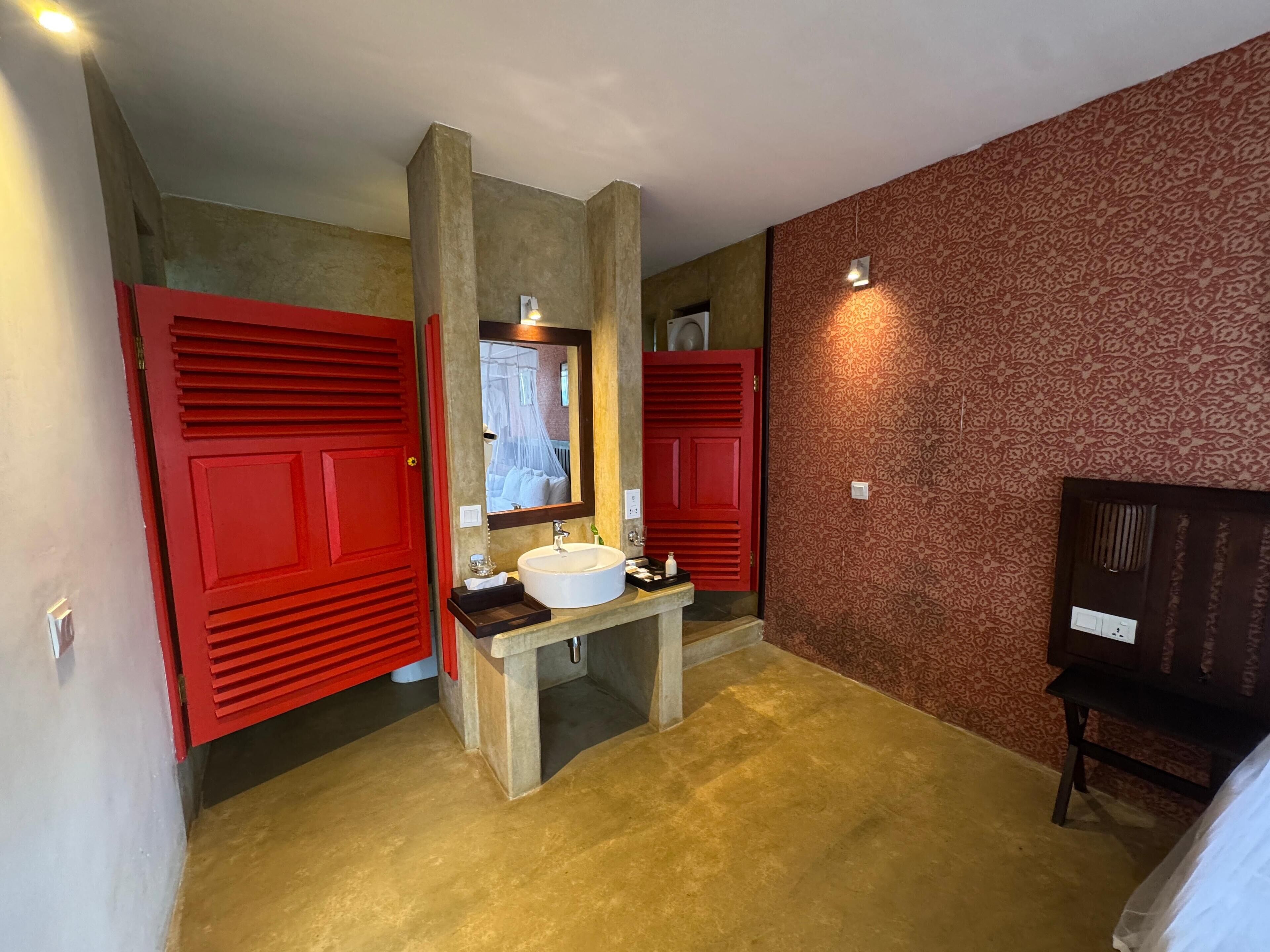 A bathroom with a large mirror, a sink, and two red doors.