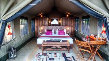 Een tent met een bed, een houten bureau en een stoel.