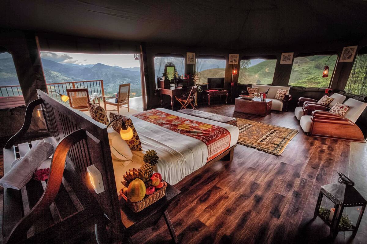 Une chambre spacieuse avec un grand lit, un coin salon et une vue sur les montagnes.