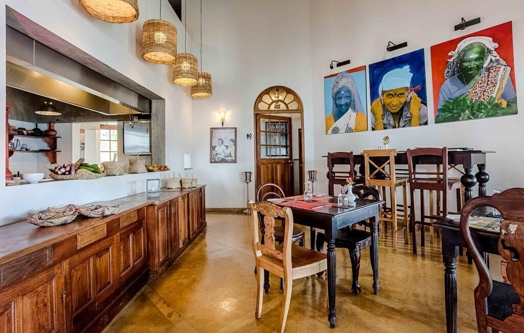 A dining area with wooden furniture, a long counter, and a large painting on the wall.
