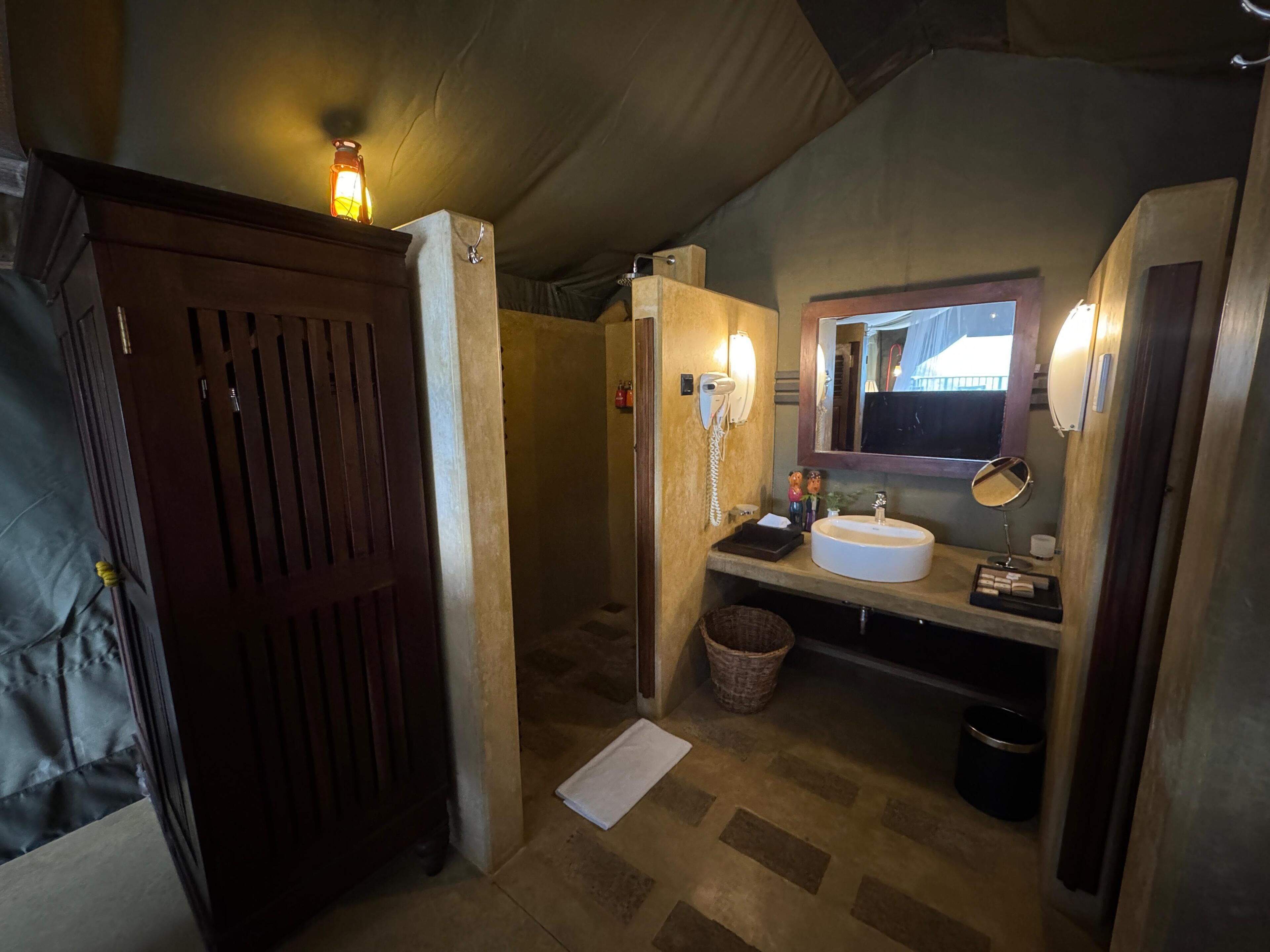 A compact bathroom with a wooden door, a white sink, a mirror, and a towel on the floor.