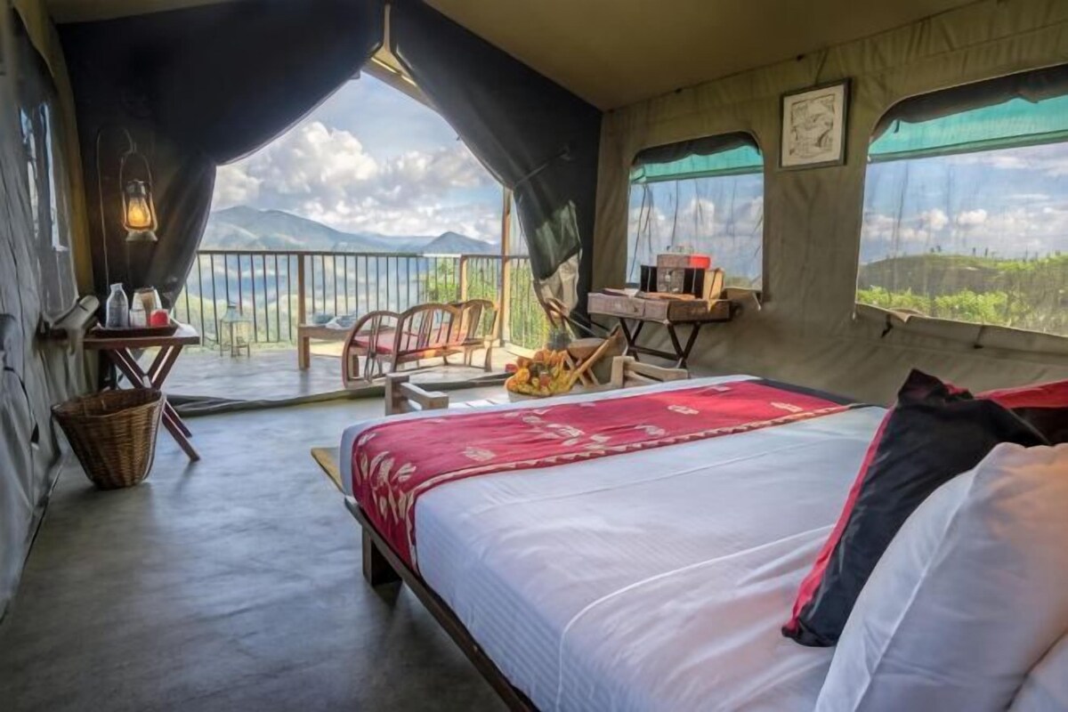A bedroom with a bed, a desk, and a view of the outdoors.