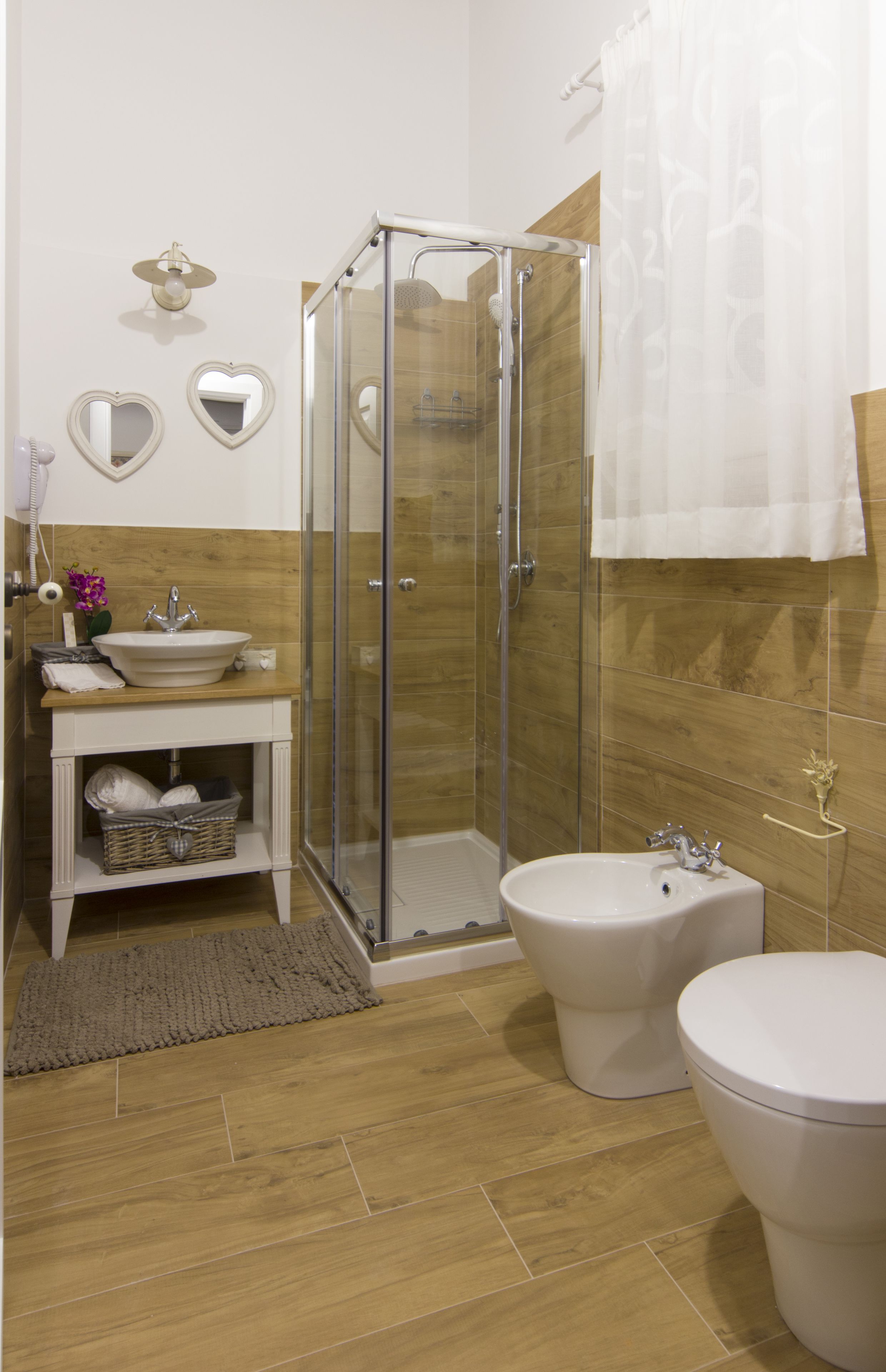 A bathroom with a glass-enclosed shower, a sink, a bidet, and a toilet.