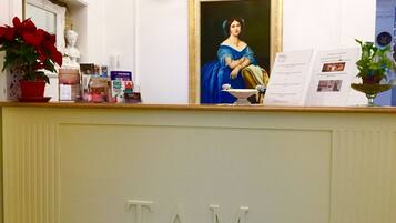 A reception desk with the name "TAM" engraved on it, a framed portrait, and various informational brochures.