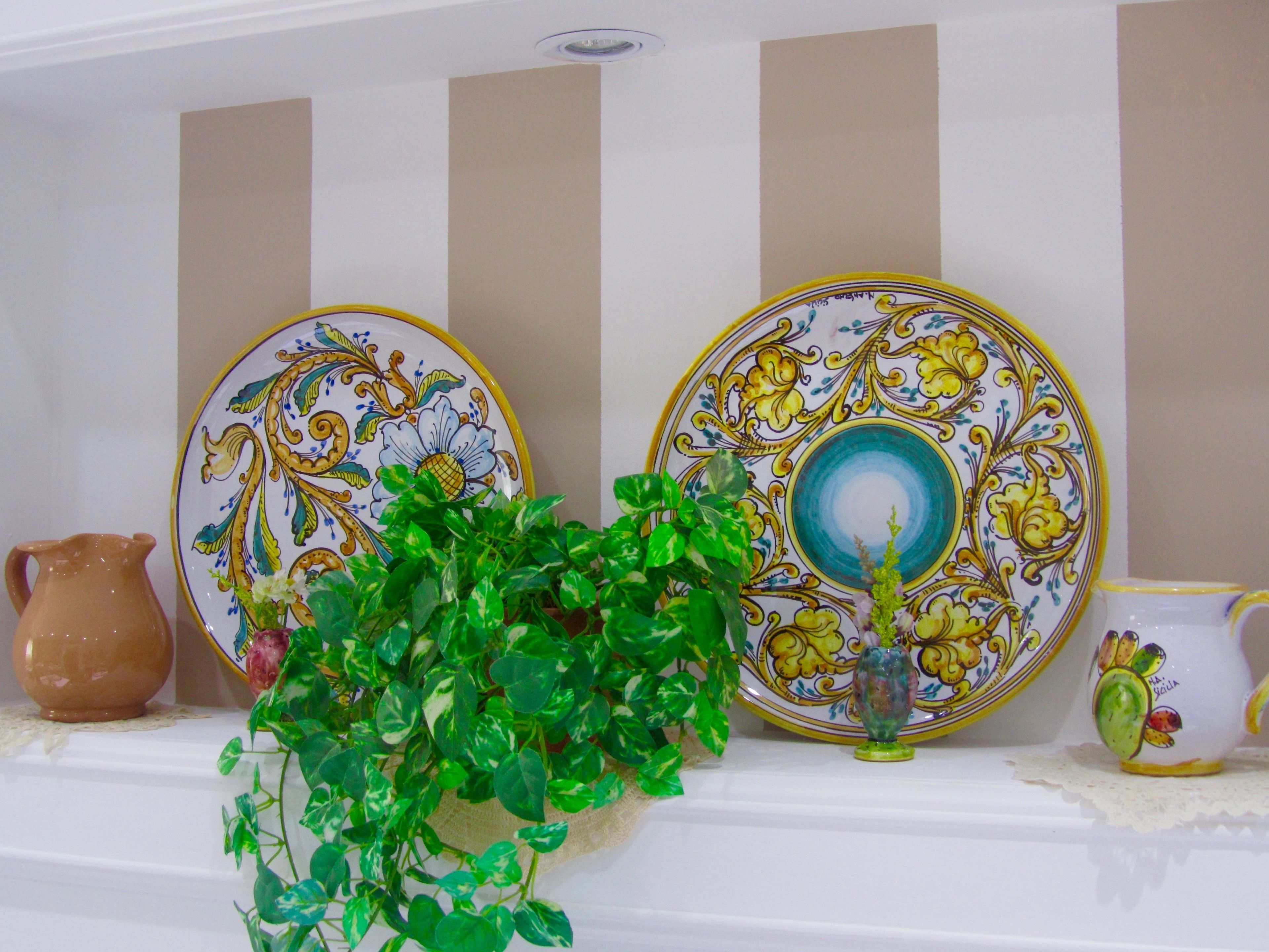 A shelf with decorative plates, a pitcher, and a potted plant.