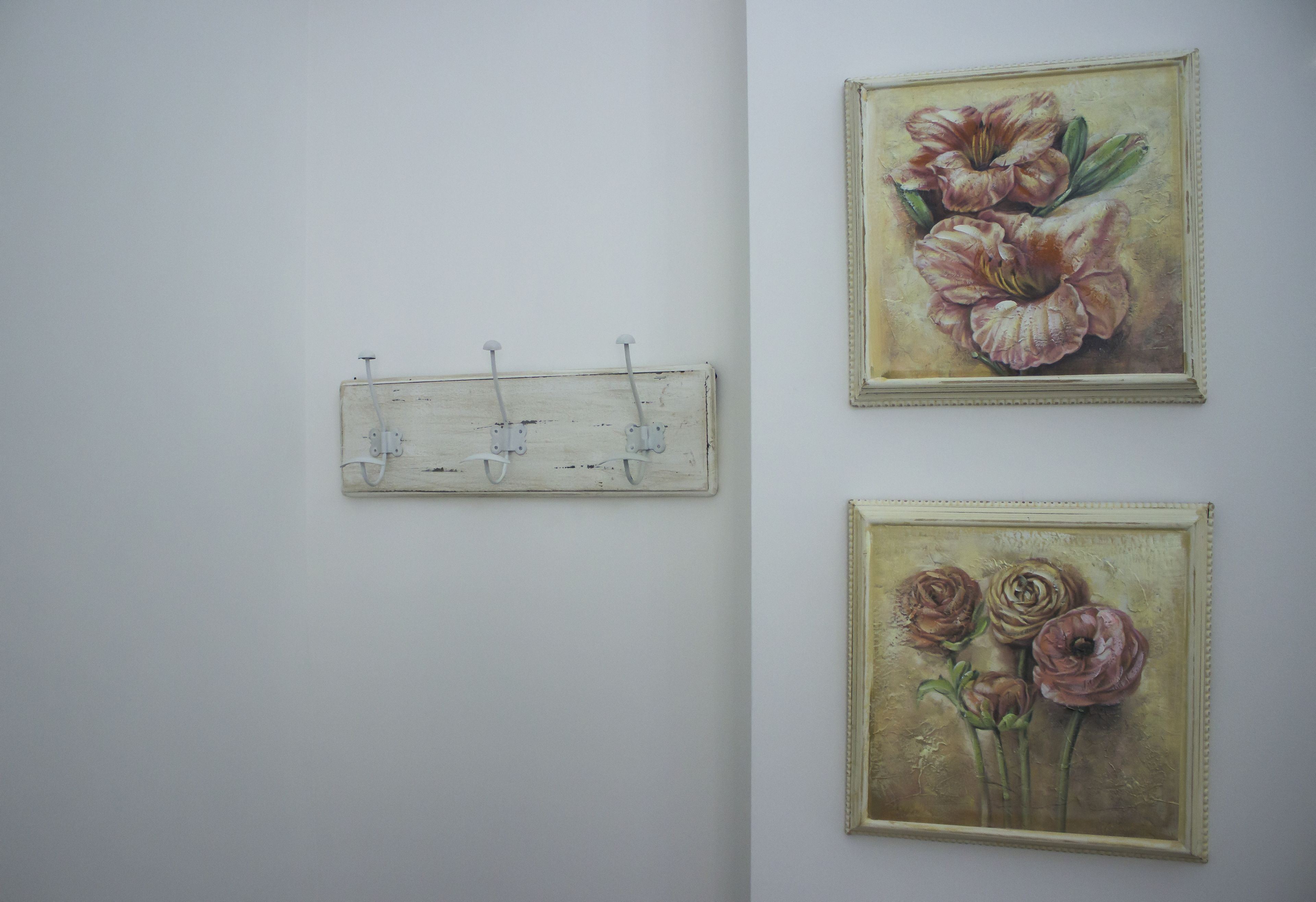Two framed floral paintings on a plain wall.