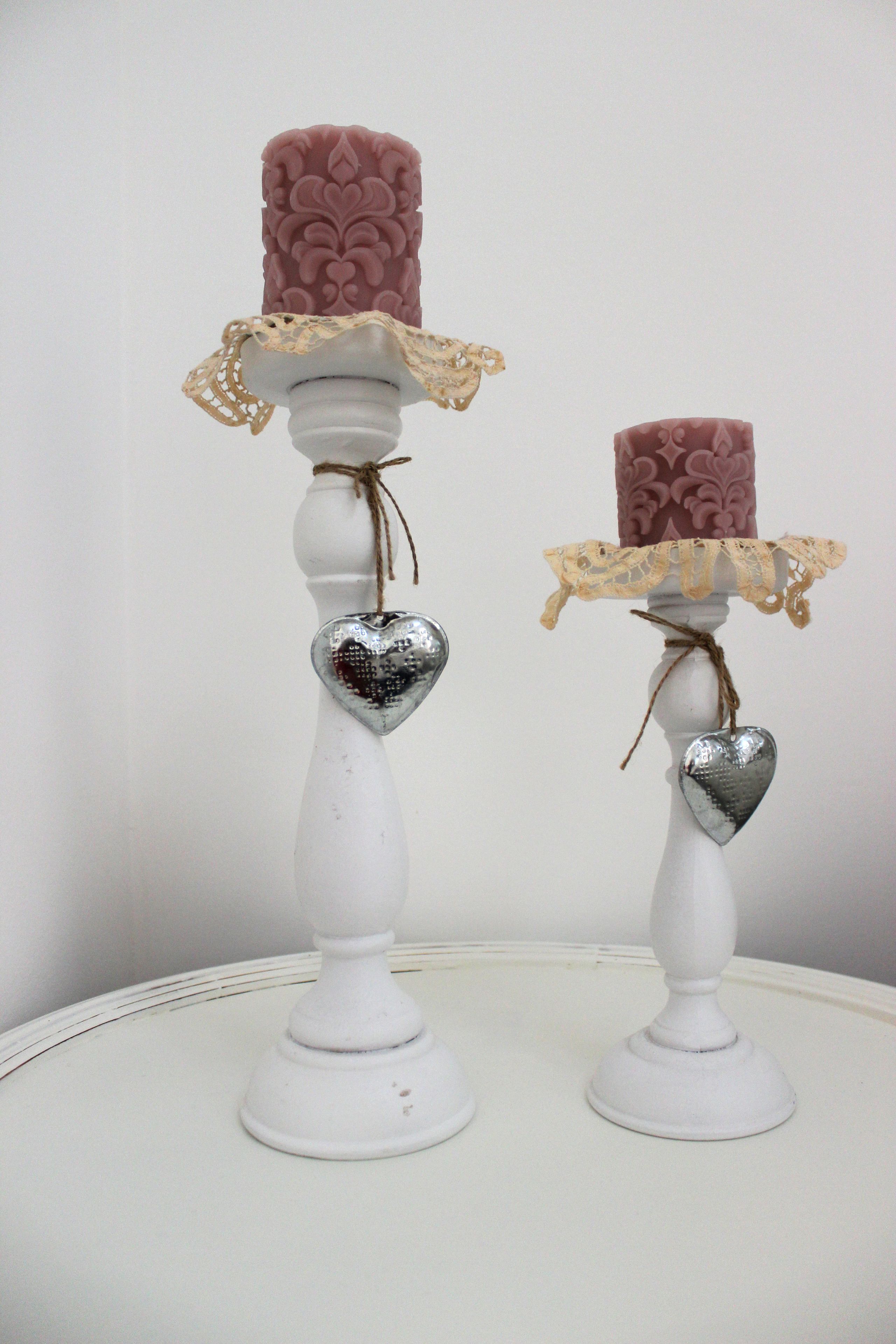 Twee witte kandelaars met decoratieve details.