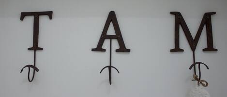 Tres letras de metal, T, A y M, colocadas en una pared.