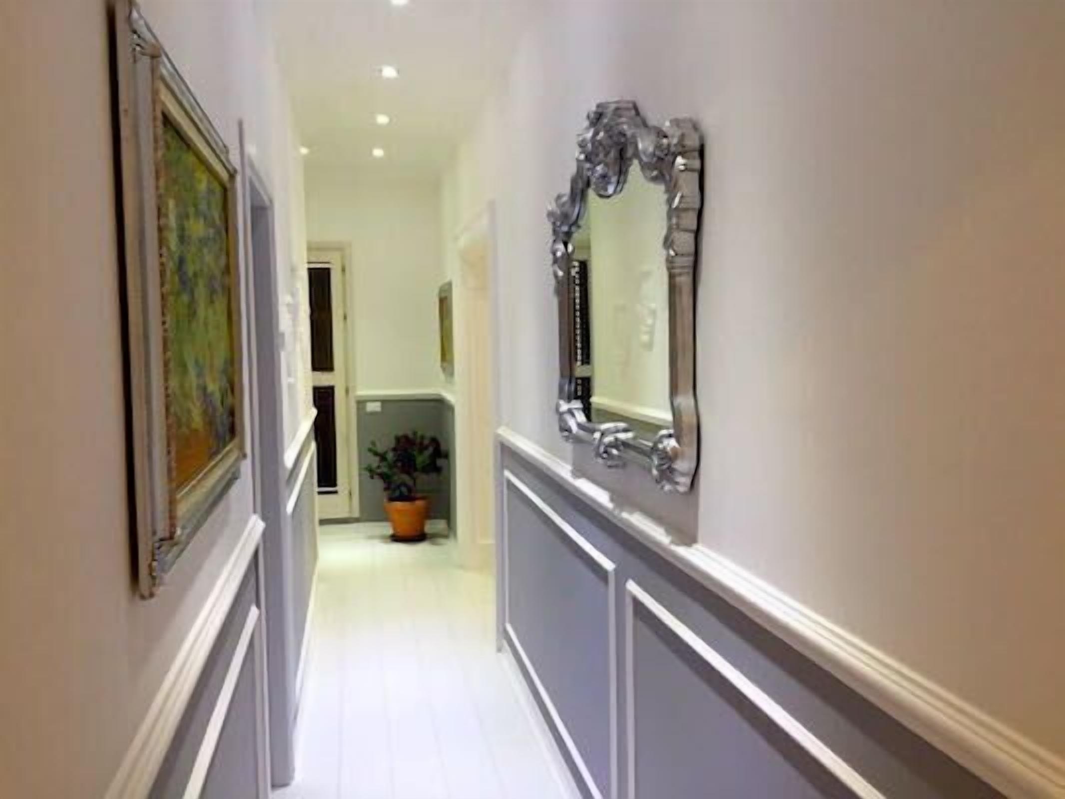 Un couloir avec un grand miroir et un tableau encadré accroché au mur.