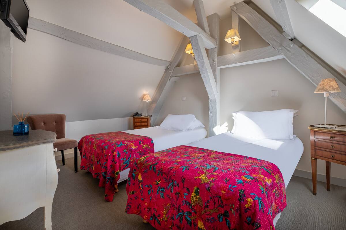 A room with two beds, a desk, and a chair.