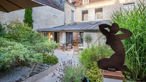 Ein Innenhof mit Steinmauern, einer Metallskulptur und Außenmöbeln.