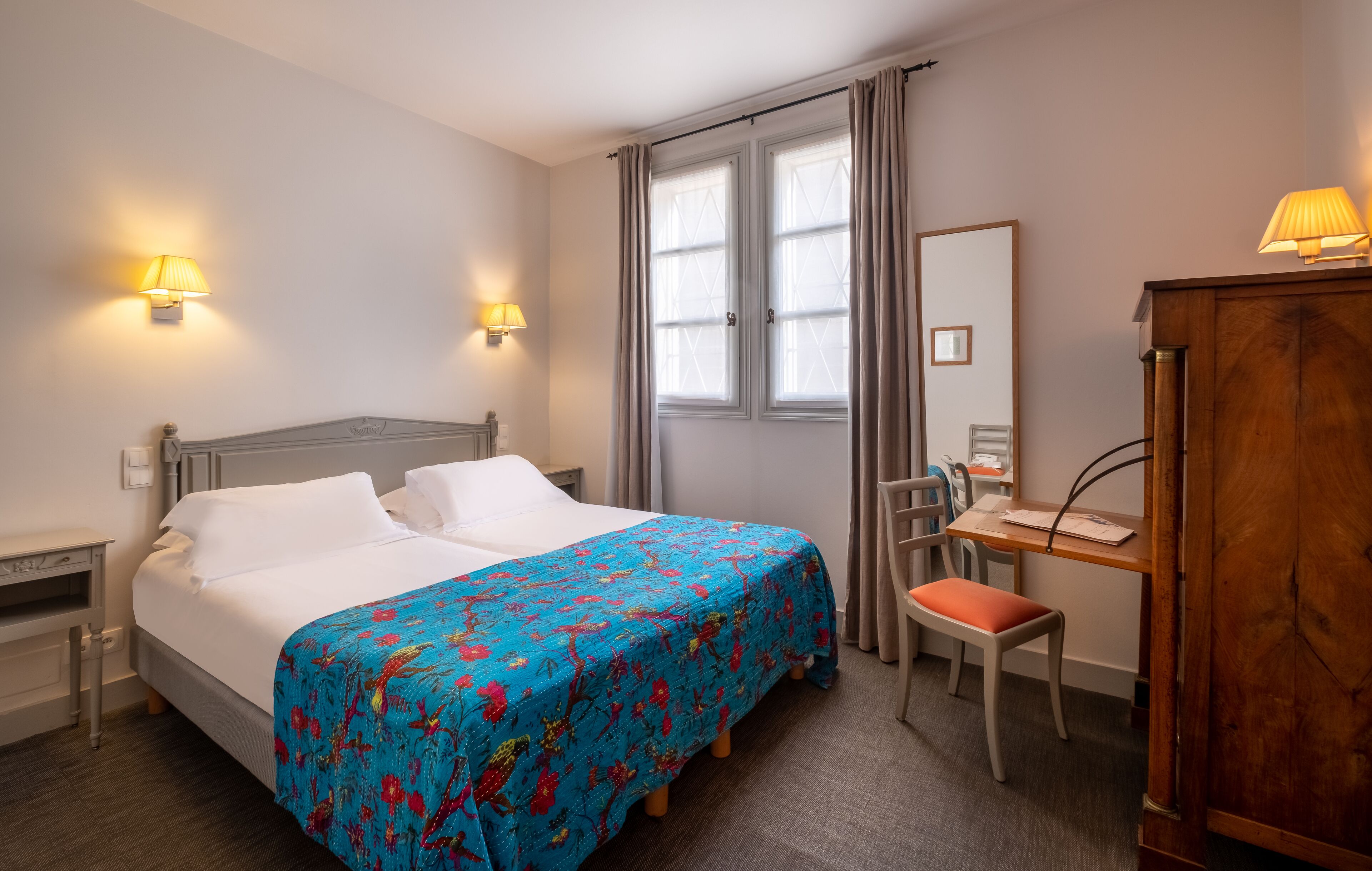 Una habitación de hotel con cama, escritorio, silla y un armario de madera.