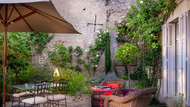 Eine Terrasse im Freien mit Korbmöbeln, einem Tisch und einem Sonnenschirm.