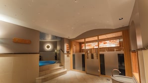 A modern bathroom with a bathtub, a shower area, and a glass-enclosed vanity. - Hotel Ulli (Lech am Arlberg)