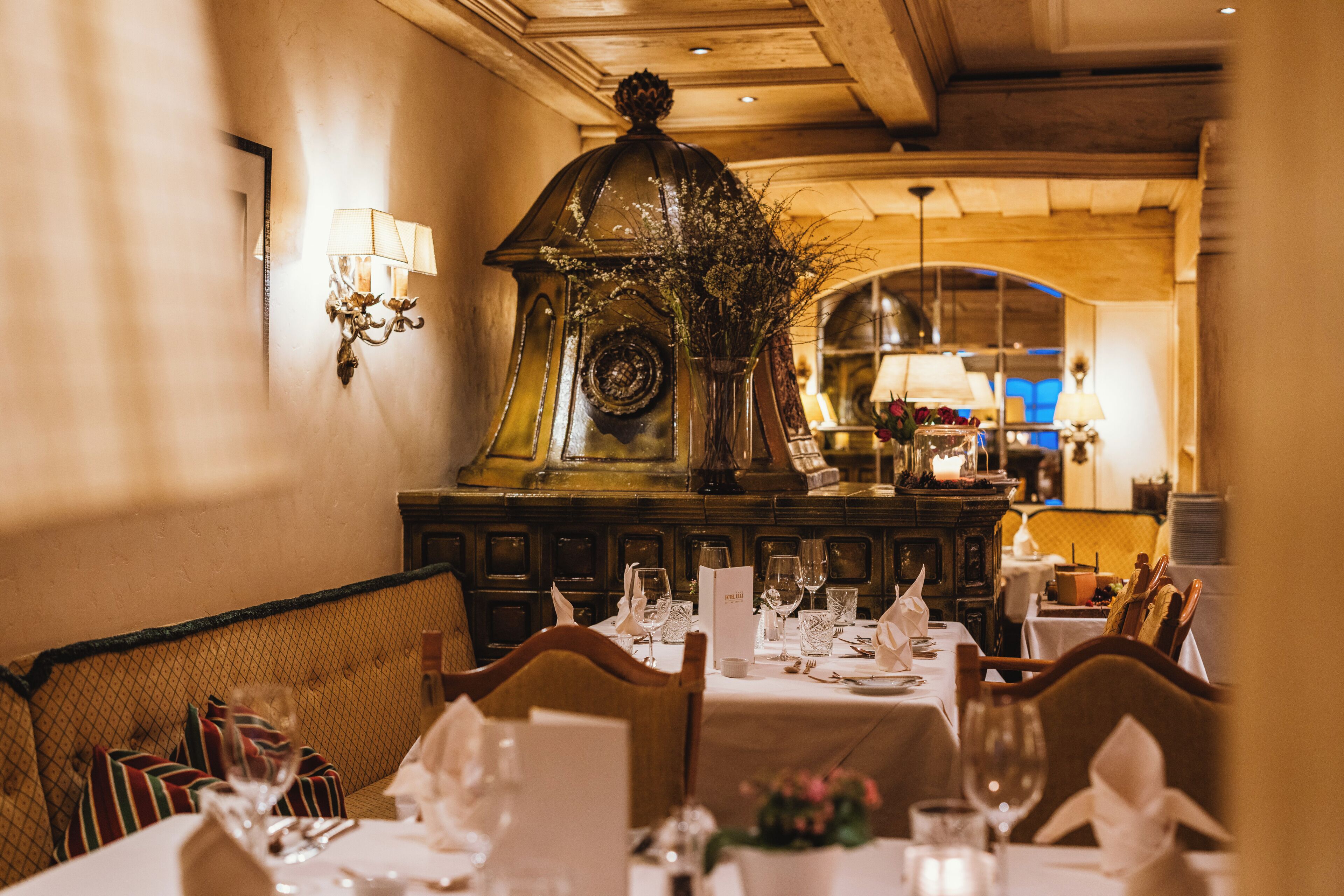 Een restaurant met gedekte tafels, een decoratieve wandklok en een kroonluchter.