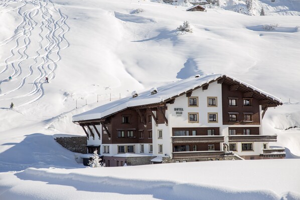 Un hotel de varios pisos con techo inclinado, situado en una zona montañosa nevada.