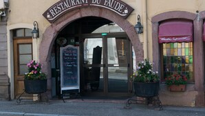Ein Restaurantzugang mit Bogenwegweiser, einer Kreidetafel mit Speisekarte und Kübelpflanzen.