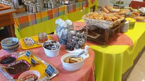Ein reichhaltiges Buffet mit verschiedenen Speisen und Besteck, darunter Brot, Gebäck und Soßen.
