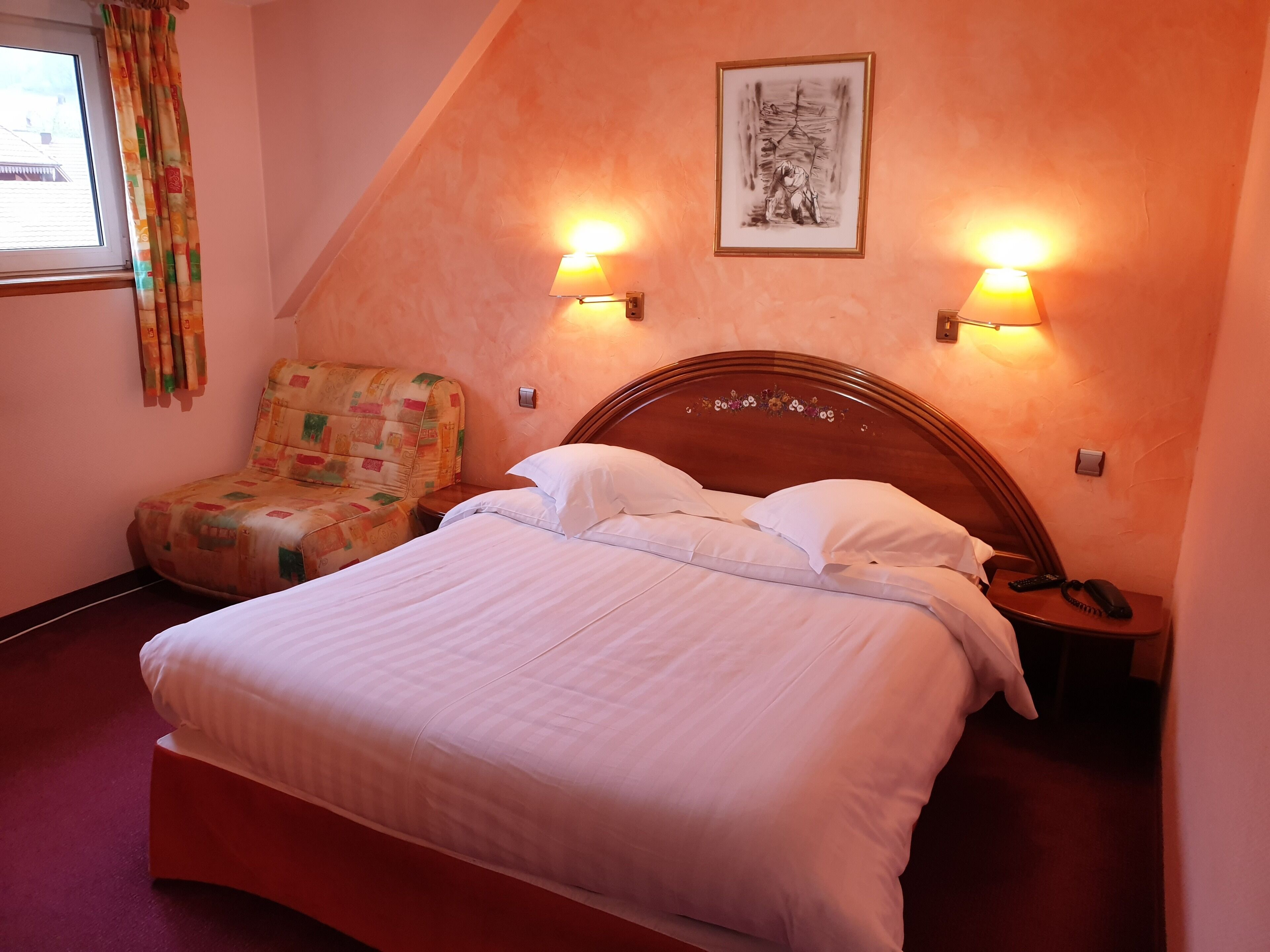 A neatly made bed with white linens, a wooden headboard, and two bedside lamps.