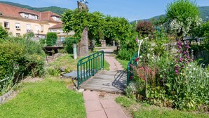 Ein Gartenweg, der zu einer hölzernen Brücke mit Metallgeländer führt.