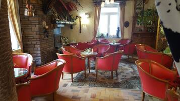 Een knus interieur met rode leren fauteuils, een open haard en een groot raam.