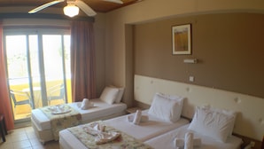 Habitación de hotel con dos camas, ventilador de techo y vista al exterior a través de una puerta corrediza.