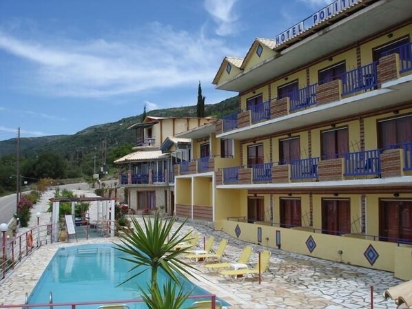 A hotel with a swimming pool, multiple balconies, and a view of the surrounding landscape. - Politia Hotel (Lefkada)