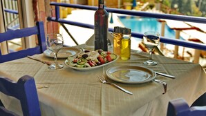 Una mesa dispuesta con un plato de comida, dos copas de vino, una botella de vino y una botella de aceite de oliva.