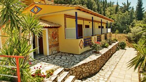 Un edificio amarillo con un camino de piedra y una pared de piedra.