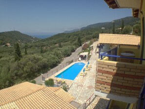 A pool area with a clear view of the surrounding landscape, including a road and distant hills. - Politia Hotel (Lefkada)