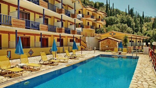 Un hotel con piscina, varios balcones y sillas de sol.