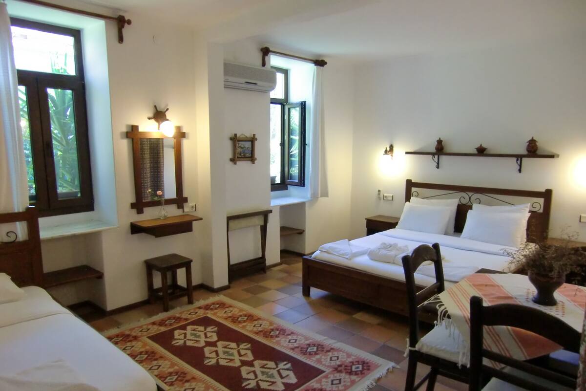 A bedroom with a bed, bedside tables, a mirror, a window, and a wall-mounted shelf.
