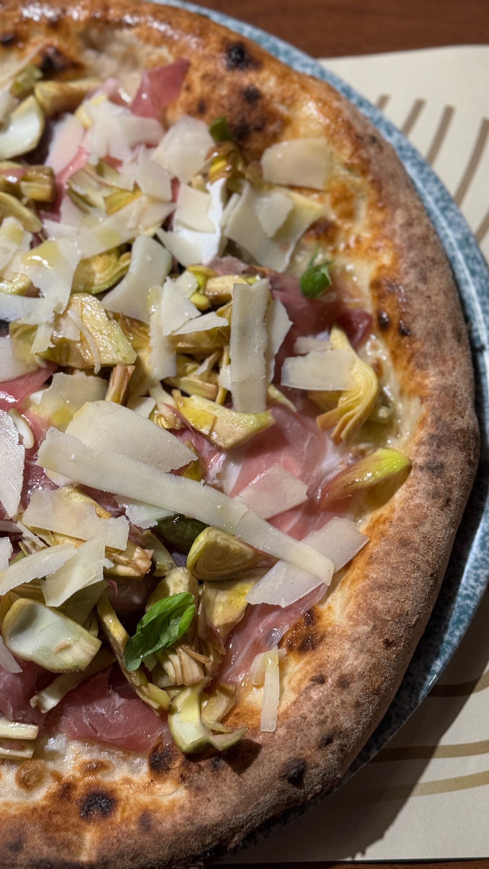Pizza, jossa on erilaisia täytteitä, tarjoiltuna pyöreällä, matalalla vadilla.
