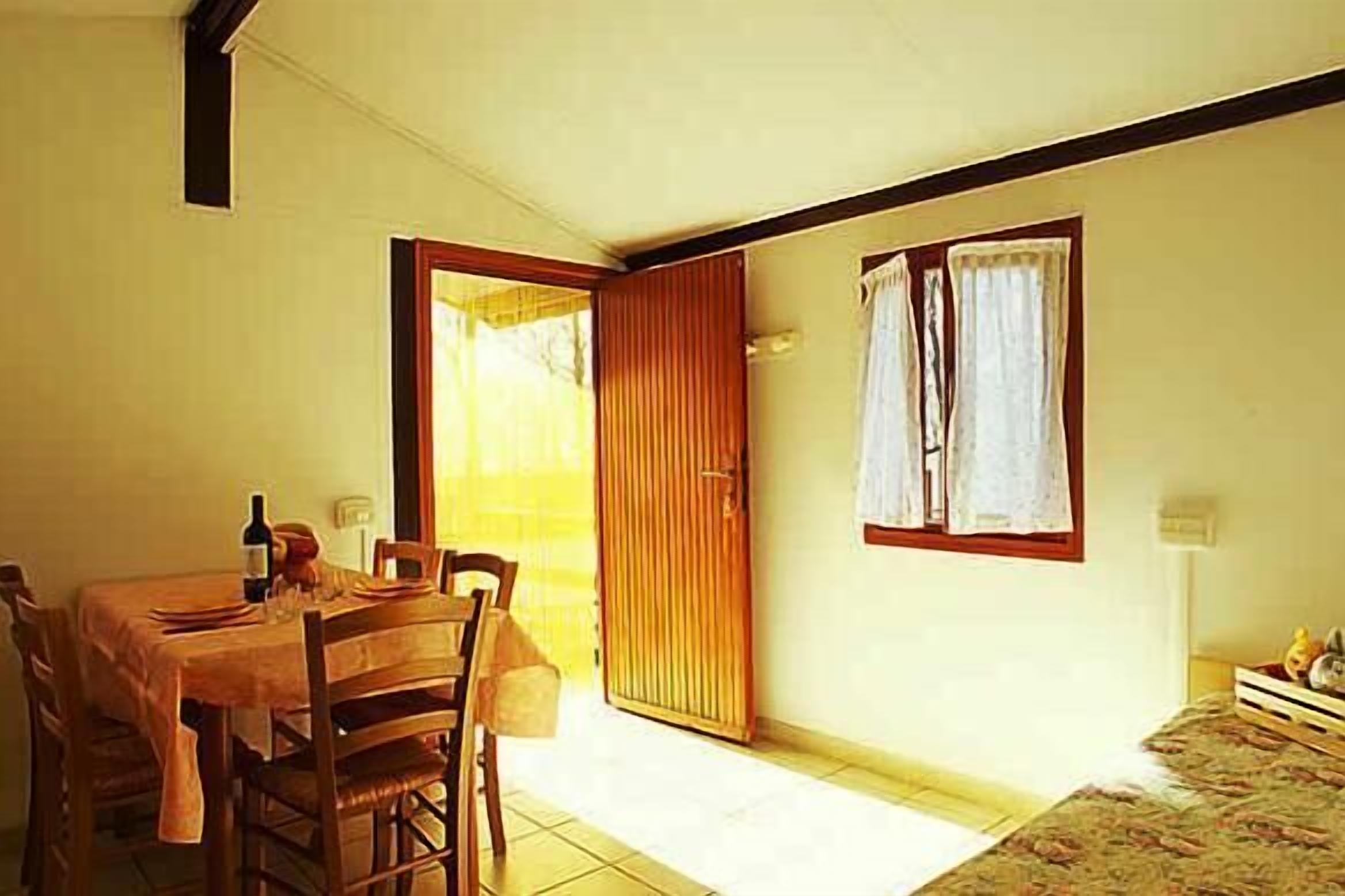 A dining area with a wooden table and chairs, a sliding door, and a window with curtains.