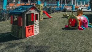 Un área de juegos infantiles con una casita, toboganes y estructuras de juego coloridas.