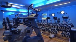 Un gimnasio con máquinas de cardio, mancuernas y equipamiento para ejercicio.