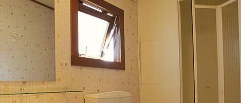 A bathroom with a sink, toilet, and a window above the toilet.