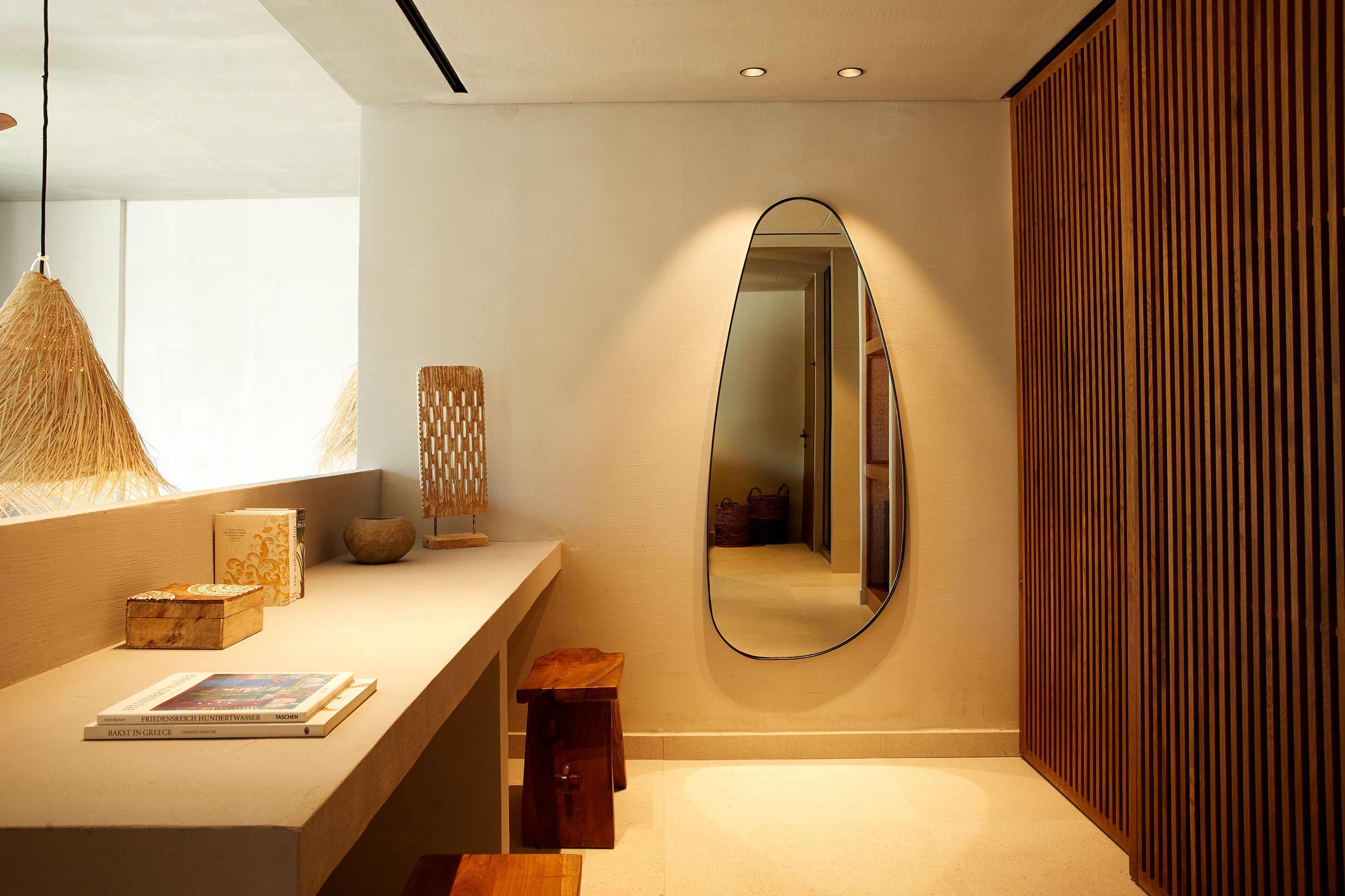 A modern bathroom with a large mirror, a wooden slat wall, and a light fixture.