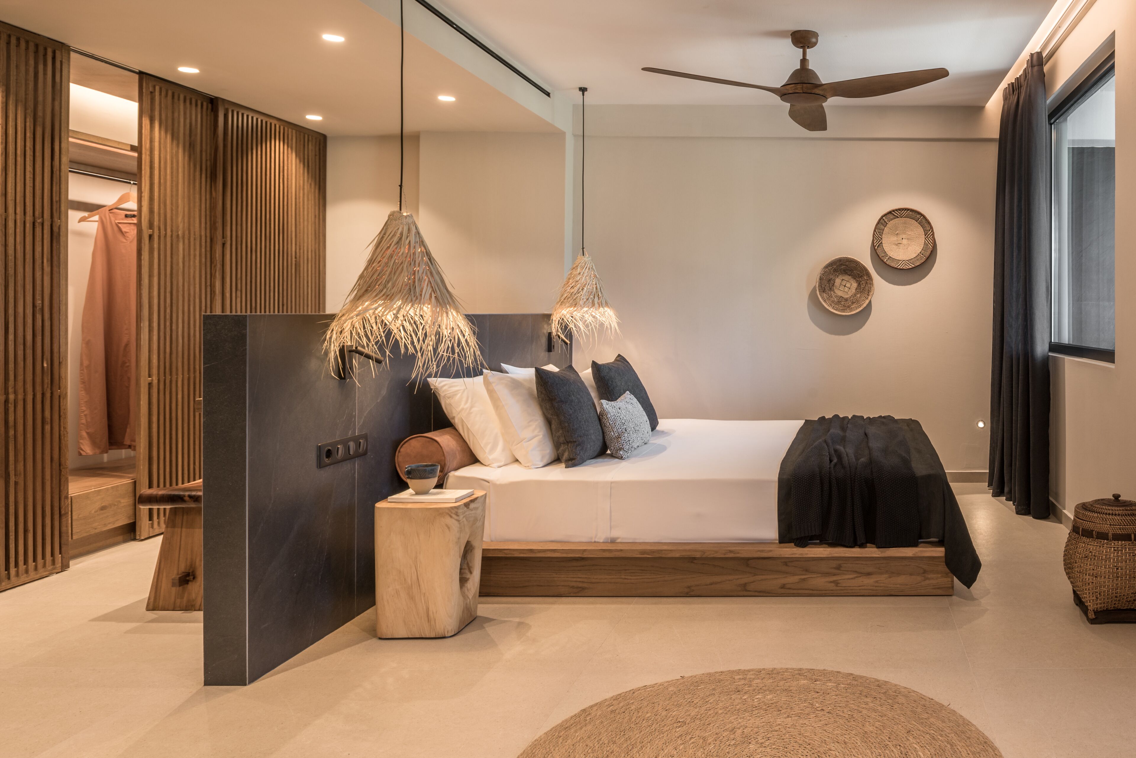 Een moderne slaapkamer met een bed, houten lambrisering, een plafondventilator en een groot raam.