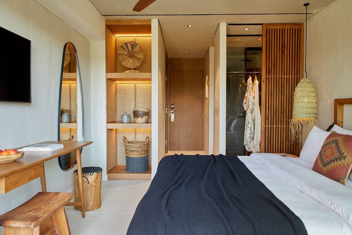Un dormitorio moderno con una cama grande, un escritorio de madera, un espejo y un armario.
