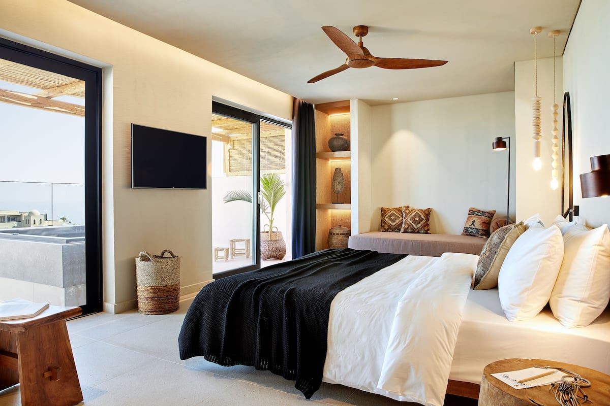 Un dormitorio moderno con cama, mesita de noche y ventilador de techo.