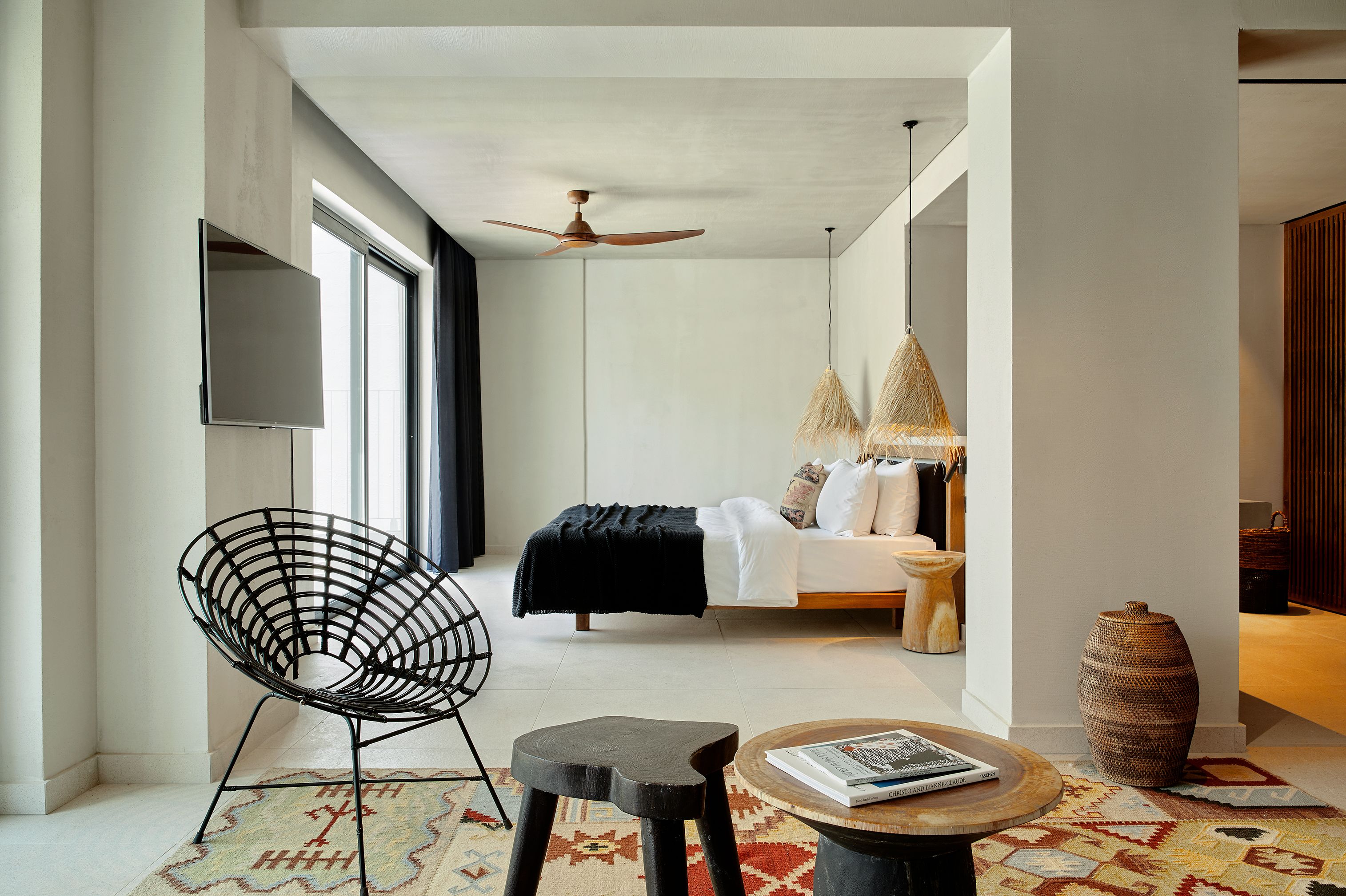 A modern bedroom with a bed, a black chair, a round table, and a large vase.
