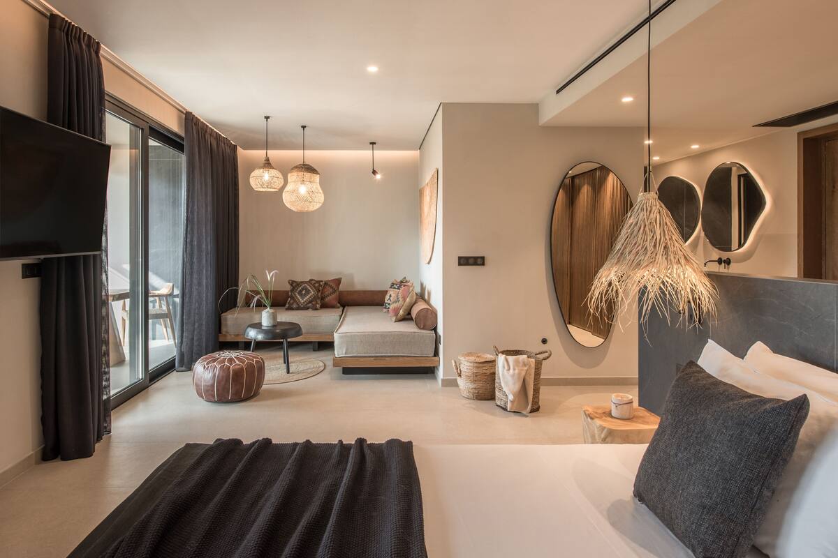 Una habitación de hotel moderna con una cama grande, un sofá, un comedor y un televisor.